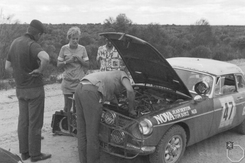 The holed radiator is resting against Jean Denton’s legs as Tom Boyce continues ﬁtting the radiator to the M G.